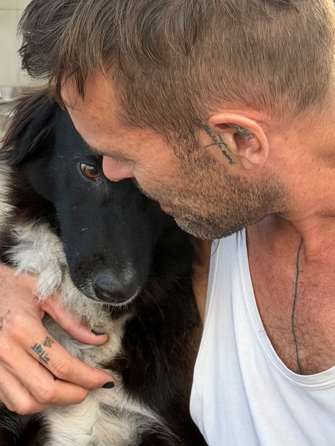Stephan Mairesse face to face with a black and white dog, close up