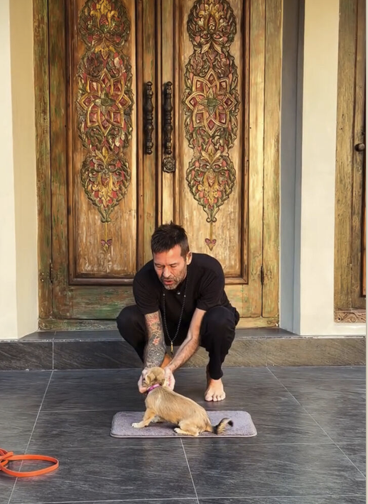 Stephan Mairesse crouching with a small dog on a mat