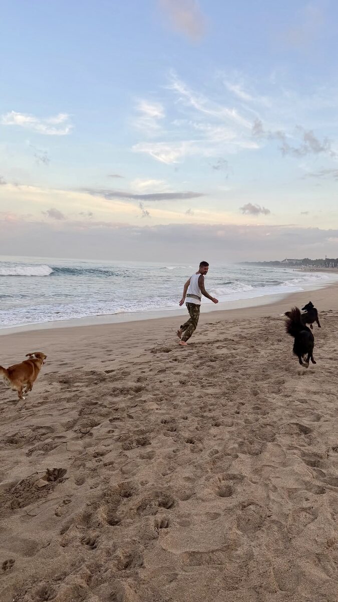 Stephan Mairesse running on the beach with dogs at sunset